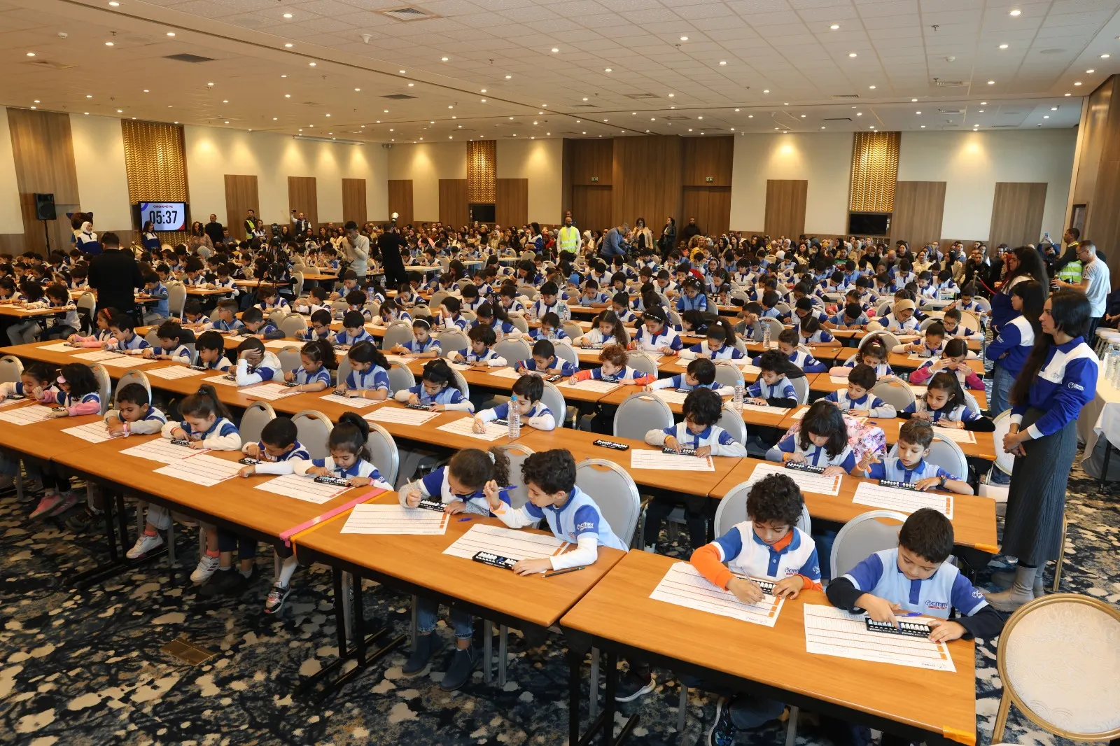 Grande salle de compétition remplie de centaines d'enfants concentrés sur leur abacus